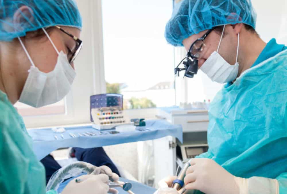 Zwei Chirurgen behandeln einen Patienten im Operationssaal des Zahnarztes Augsburg.