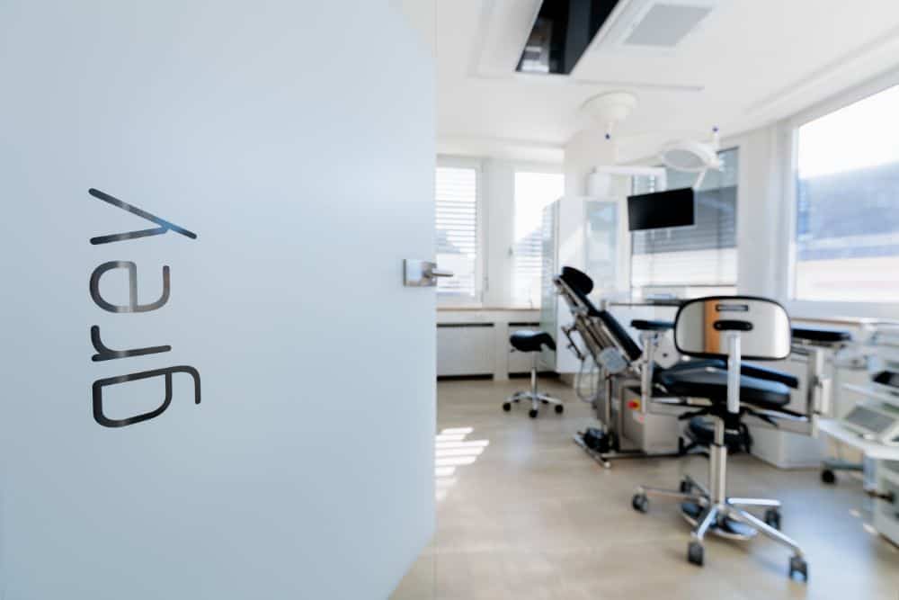 Ein Raum in einer Zahnarztpraxis mit einem grauen Schild, auf dem für die Dienstleistungen von Zahnarzt Augsburg geworben wird.