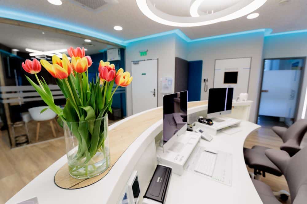 Der Empfangsbereich einer Zahnarztpraxis in Augsburg, geschmückt mit einer Vase voller Tulpen.