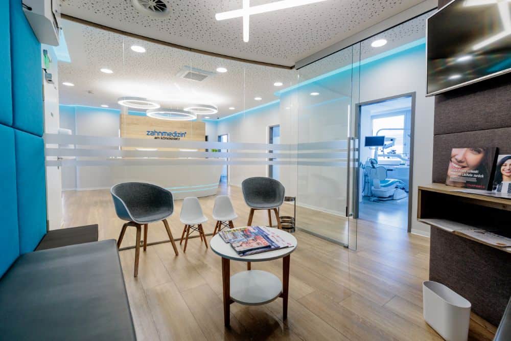 Der Empfangsbereich einer Zahnarztpraxis in Augsburg mit blauen Wänden und Stühlen.